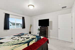 Primary bedroom featuring light colored carpet and baseboards