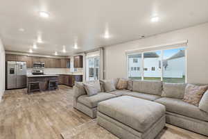 Living area with light wood finished floors and recessed lighting