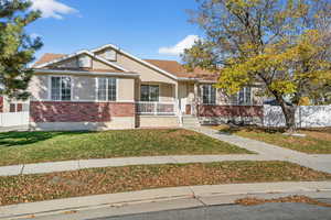 View of front of property featuring brick siding, a porch, and stucco siding
