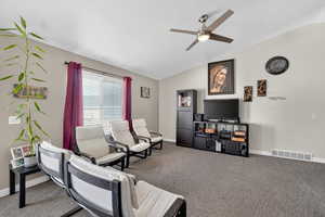 Living room featuring vaulted ceiling, carpet floors, and a ceiling fan