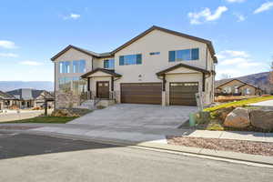 View of front of home with a mountain view, a garage, driveway, stucco siding, and stone siding