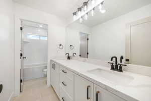 Bathroom featuring double vanity, light tile patterned floors, and bathing tub / shower combination