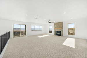 Unfurnished living room featuring light colored carpet, a fireplace, recessed lighting, and ceiling fan