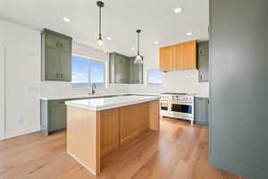 Kitchen featuring backsplash, range with two ovens, pendant lighting, recessed lighting, and light wood-type flooring