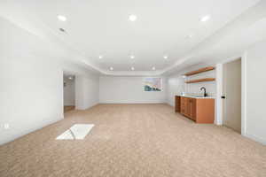 Unfurnished living room with light colored carpet, recessed lighting, and a tray ceiling