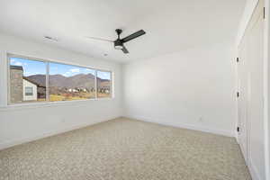 Unfurnished room featuring a mountain view, light carpet, a ceiling fan, and a textured ceiling