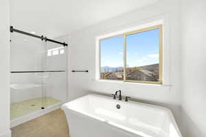Bathroom with a shower stall, a freestanding tub, a mountain view, and light tile patterned floors