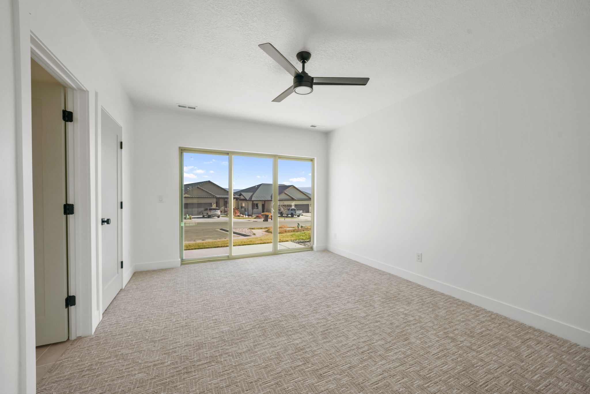 Spare room with a textured ceiling, light colored carpet, and a ceiling fan