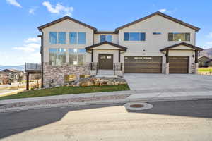 Contemporary house with a mountain view, an attached garage, concrete driveway, and stone siding
