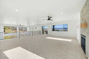 Unfurnished living room with a ceiling fan, carpet floors, a fireplace, and recessed lighting