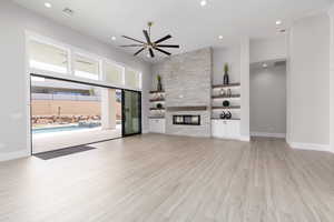 Unfurnished living room with recessed lighting, light wood finished floors, a stone fireplace, and ceiling fan
