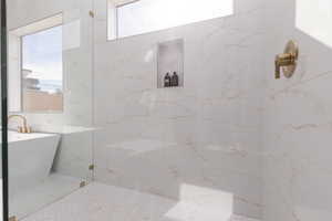 Full bath with a freestanding bath and a marble finish shower