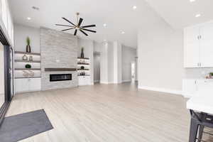 Unfurnished living room featuring light wood finished floors, recessed lighting, a large fireplace, and ceiling fan