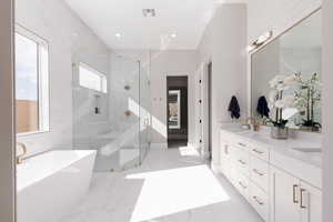 Bathroom with double vanity, a freestanding bath, a marble finish shower, light marble finish flooring, and recessed lighting