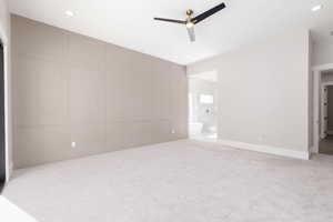 Unfurnished bedroom featuring a decorative wall, light colored carpet, recessed lighting, and ceiling fan