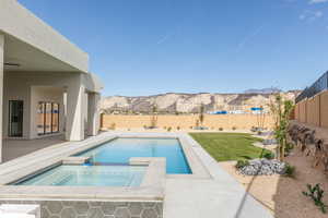 View of pool featuring a patio, a pool with connected hot tub, a fenced backyard, and a mountain view