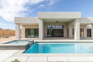 Rear view of house with a ceiling fan, a patio, stucco siding, and a pool with connected hot tub