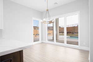 Unfurnished dining area with light wood-style flooring and a chandelier