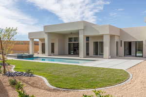 Rear view of house with ceiling fan, a patio, a pool with connected hot tub, and stucco siding