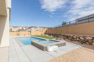 View of swimming pool with a patio, a fenced backyard, a pool with connected hot tub, and a mountain view