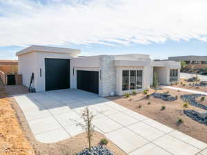 Modern home with stone siding, stucco siding, driveway, and a garage