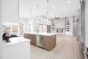 Kitchen featuring open floor plan, a center island with sink, stainless steel appliances, decorative light fixtures, and recessed lighting