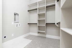 Walk in closet with light colored carpet