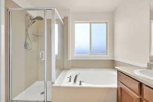 Full bathroom featuring a garden tub, vanity, and a stall shower