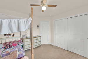 Bedroom with light colored carpet, a ceiling fan, and a closet