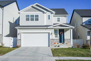 Craftsman-style house featuring stone siding, a garage, roof with shingles, concrete driveway, and a gate