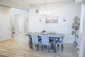 Dining area featuring a decorative wall, a chandelier, and light wood-style flooring