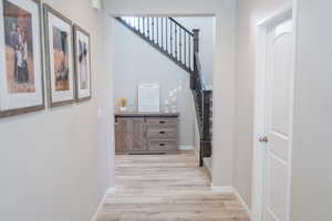 Hallway with light wood finished floors and stairway