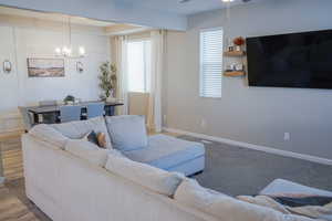Living room featuring ceiling fan, a chandelier, and a decorative wall