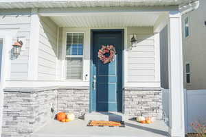 View of exterior entry featuring stone siding and covered porch