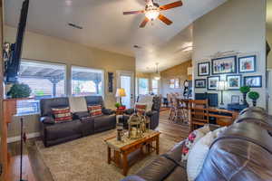 Living area featuring vaulted ceiling, wood finished floors, and a ceiling fan