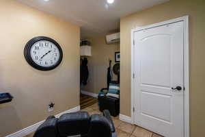 Workout room with light tile patterned flooring, a wall mounted AC, and recessed lighting