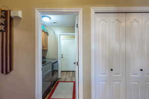 Laundry area featuring light wood finished floors, washing machine and clothes dryer, and cabinet space