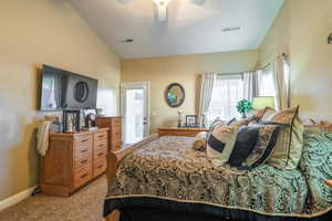 Bedroom with vaulted ceiling, light colored carpet, and ceiling fan