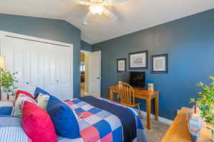 Carpeted bedroom featuring a closet, vaulted ceiling, and ceiling fan