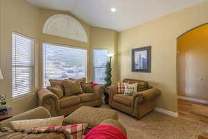 Living area with arched walkways, recessed lighting, lofted ceiling, and carpet