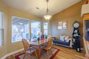 Dining area with lofted ceiling and light wood-style floors