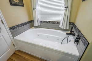 Bathroom featuring a whirlpool tub and dark wood-style flooring