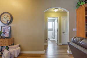 Hallway with arched walkways and wood finished floors