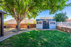 Fenced backyard featuring a storage unit