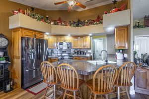 Kitchen featuring tile countertops, a peninsula, stainless steel appliances, dark wood-style floors, and a breakfast bar