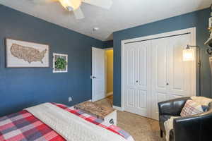 Bedroom with a textured ceiling, a closet, carpet flooring, and ceiling fan
