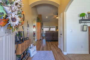 Corridor with arched walkways, wood finished floors, a high ceiling, and recessed lighting