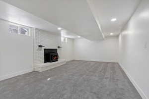 Unfurnished living room featuring light carpet, recessed lighting, and a brick fireplace