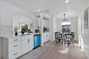 Kitchen featuring white cabinetry, light wood-type flooring, backsplash, dishwasher, and recessed lighting