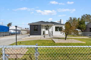 Bungalow-style home with a fenced front yard, brick siding, and a chimney
